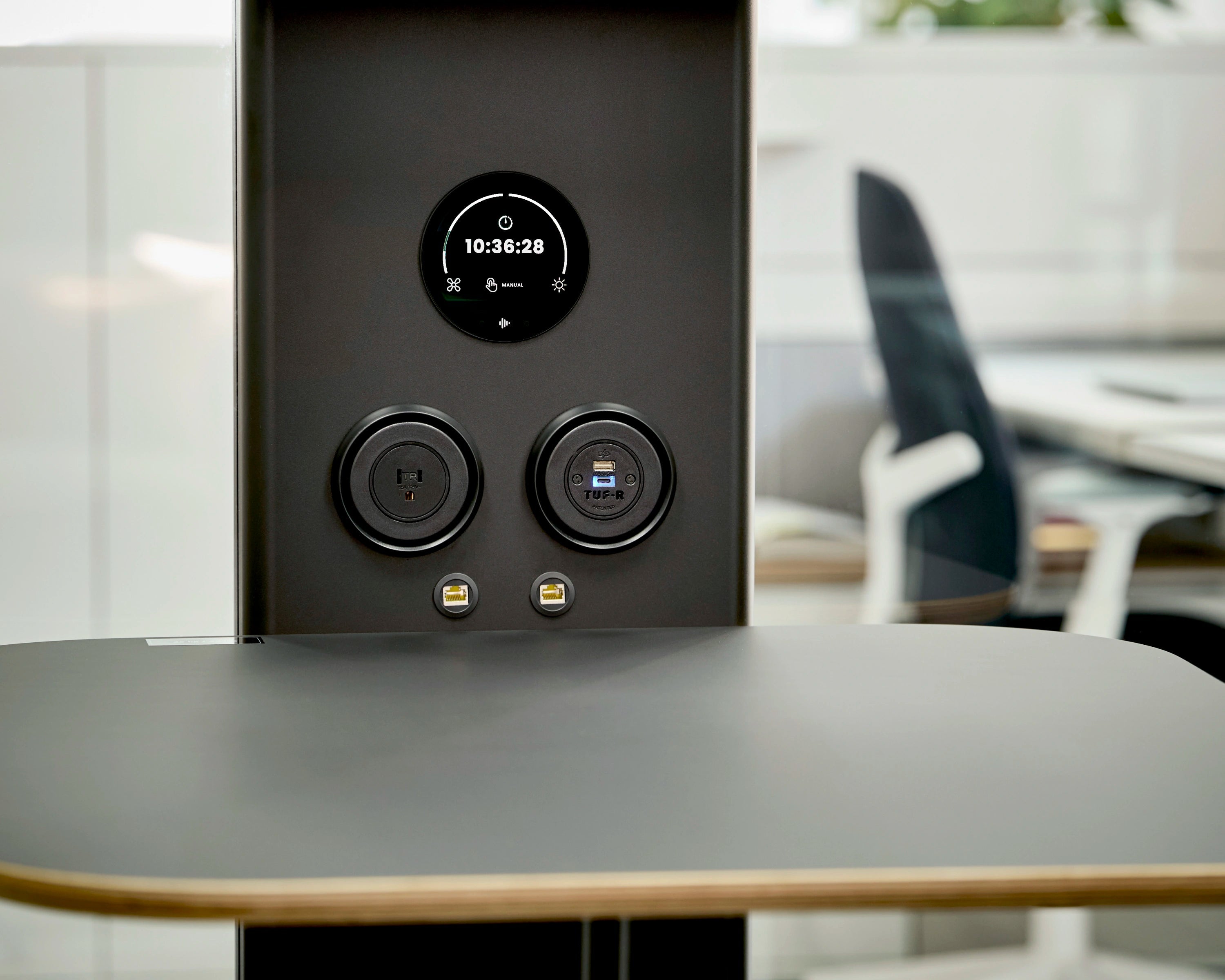 Black electronic device with digital display on a table in an office setting