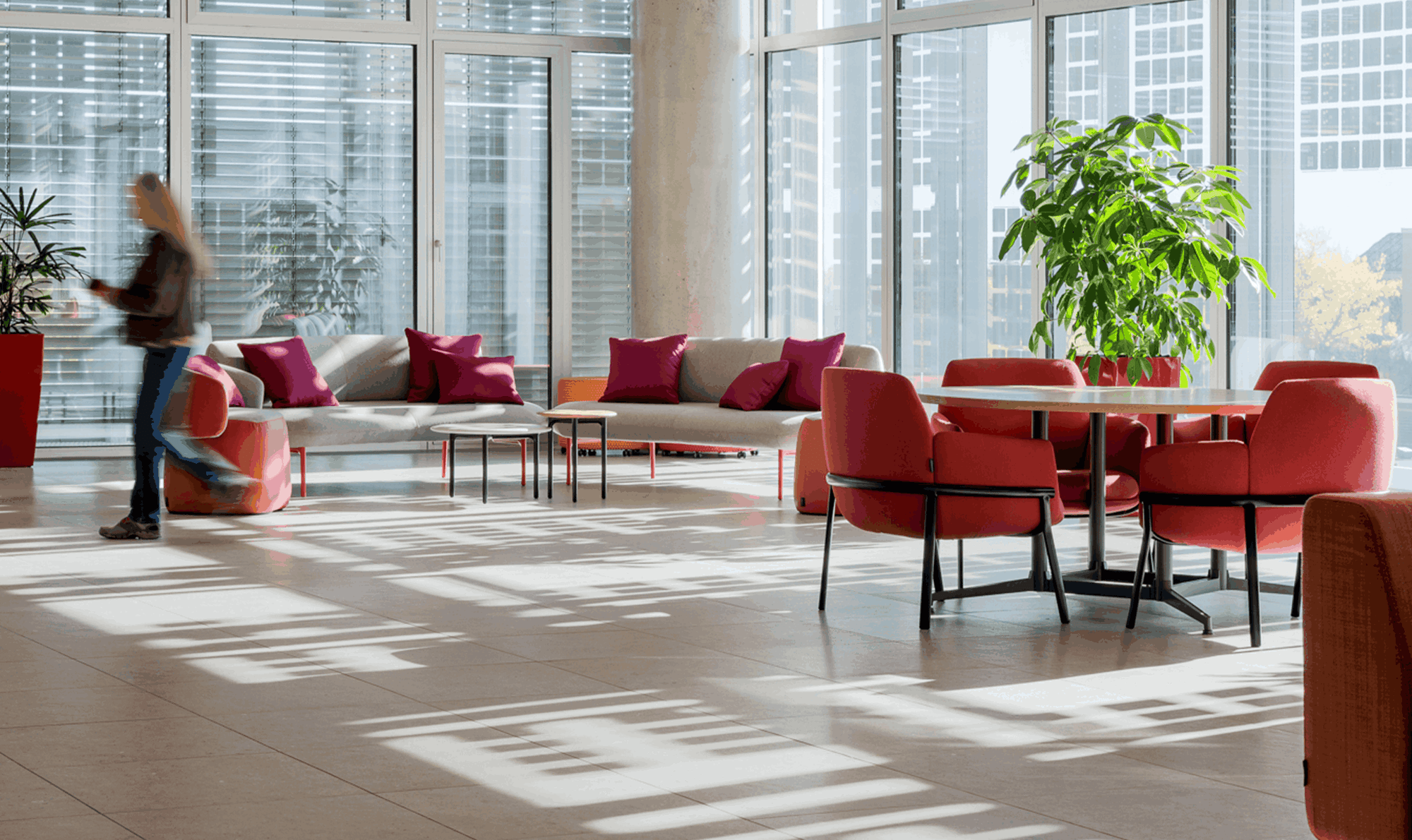 Modern office space with red chairs, a table, and large windows.