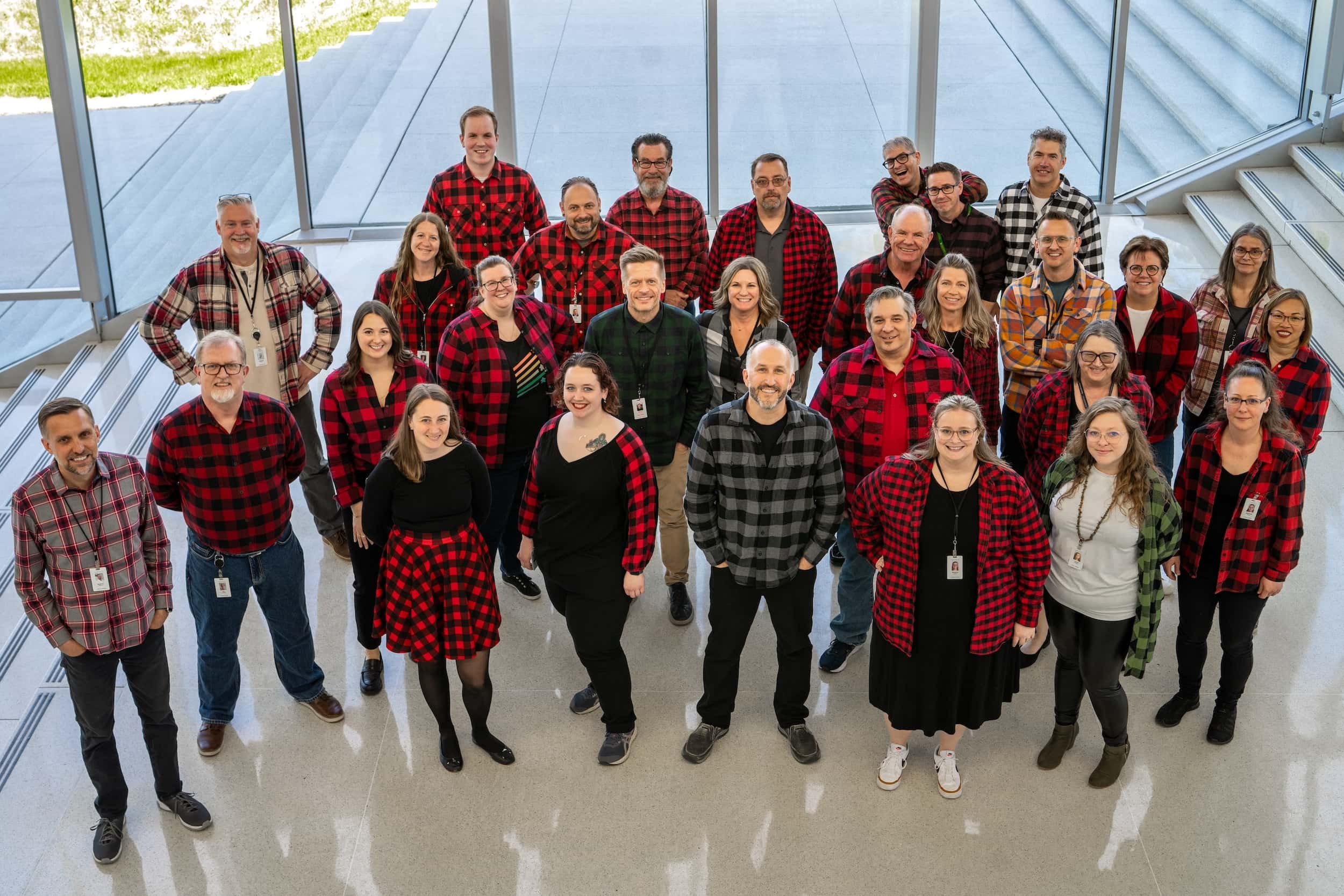 Group of people wearing red plaid shirts in a modern indoor setting