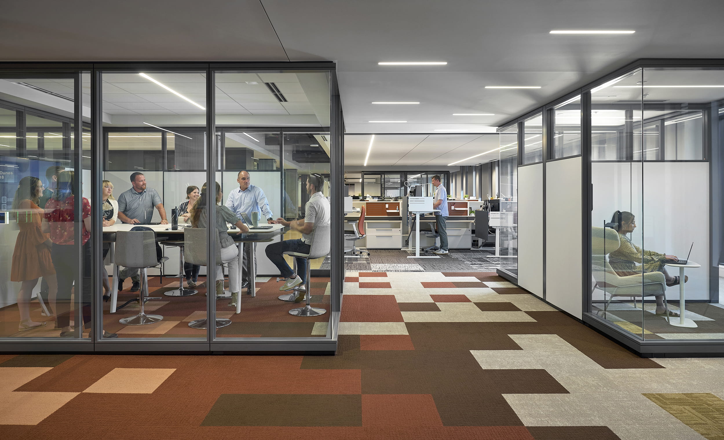 Modern office interior with glass partitions and employees working.