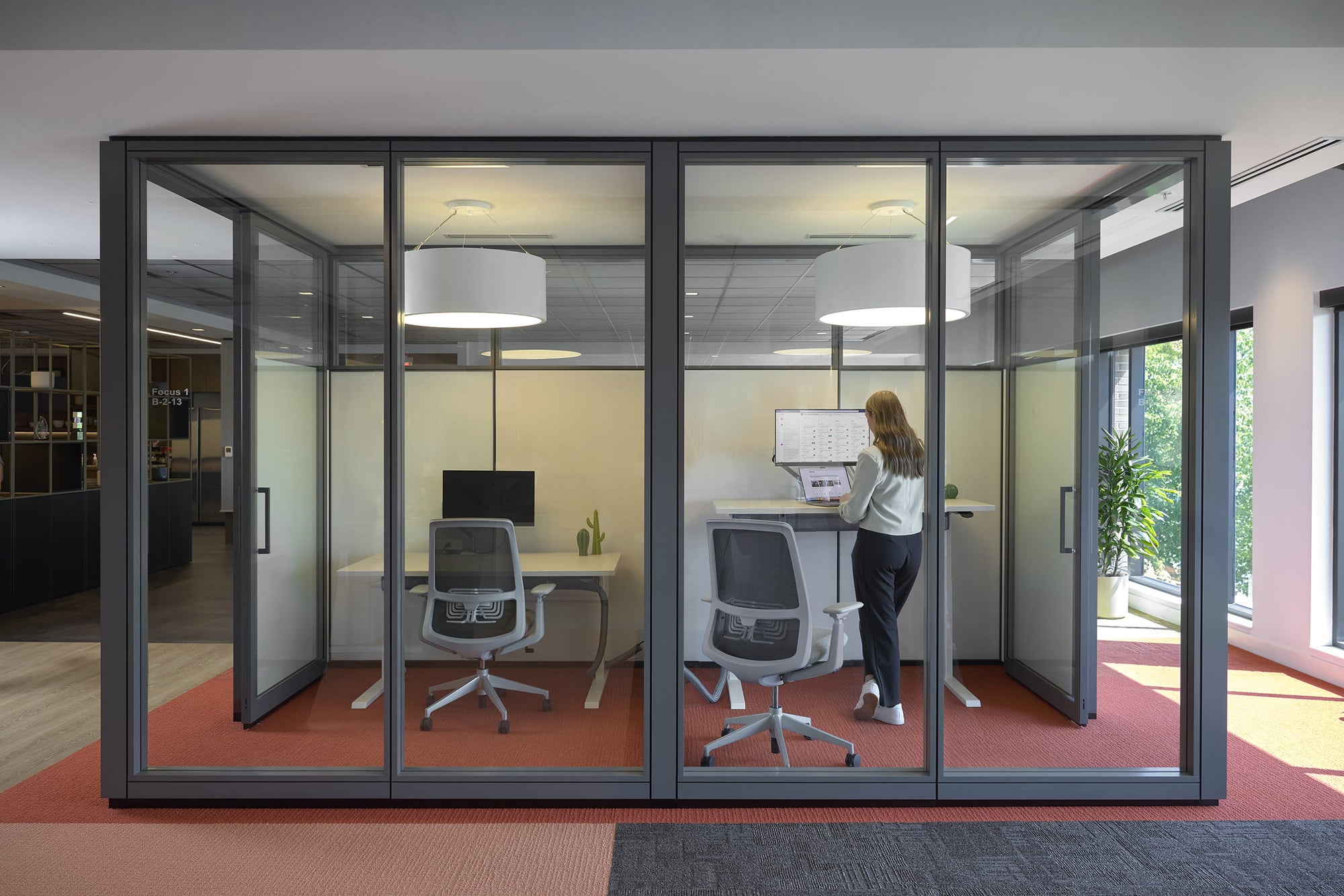 Modern office with glass partitioned office space and a person working at a desk.