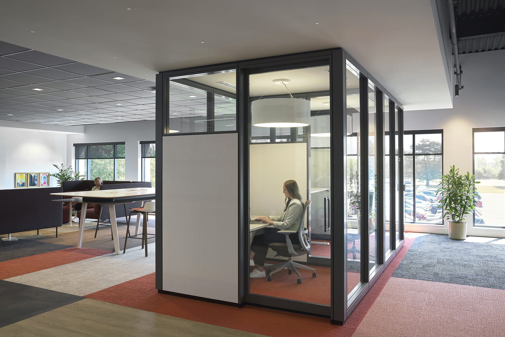 Modern office space with glass partitioned office and person working.