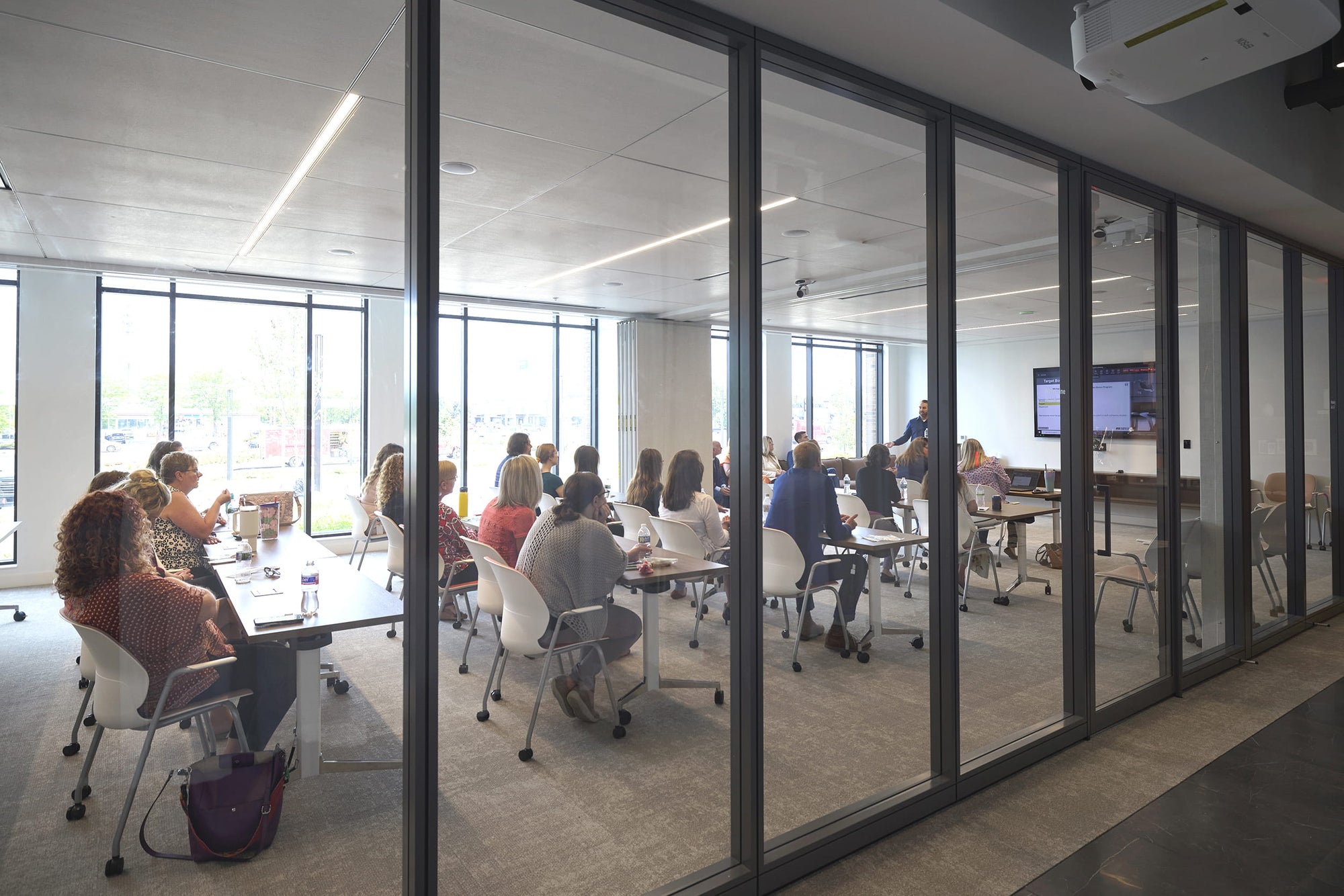 Group of people in a modern office setting with glass walls.