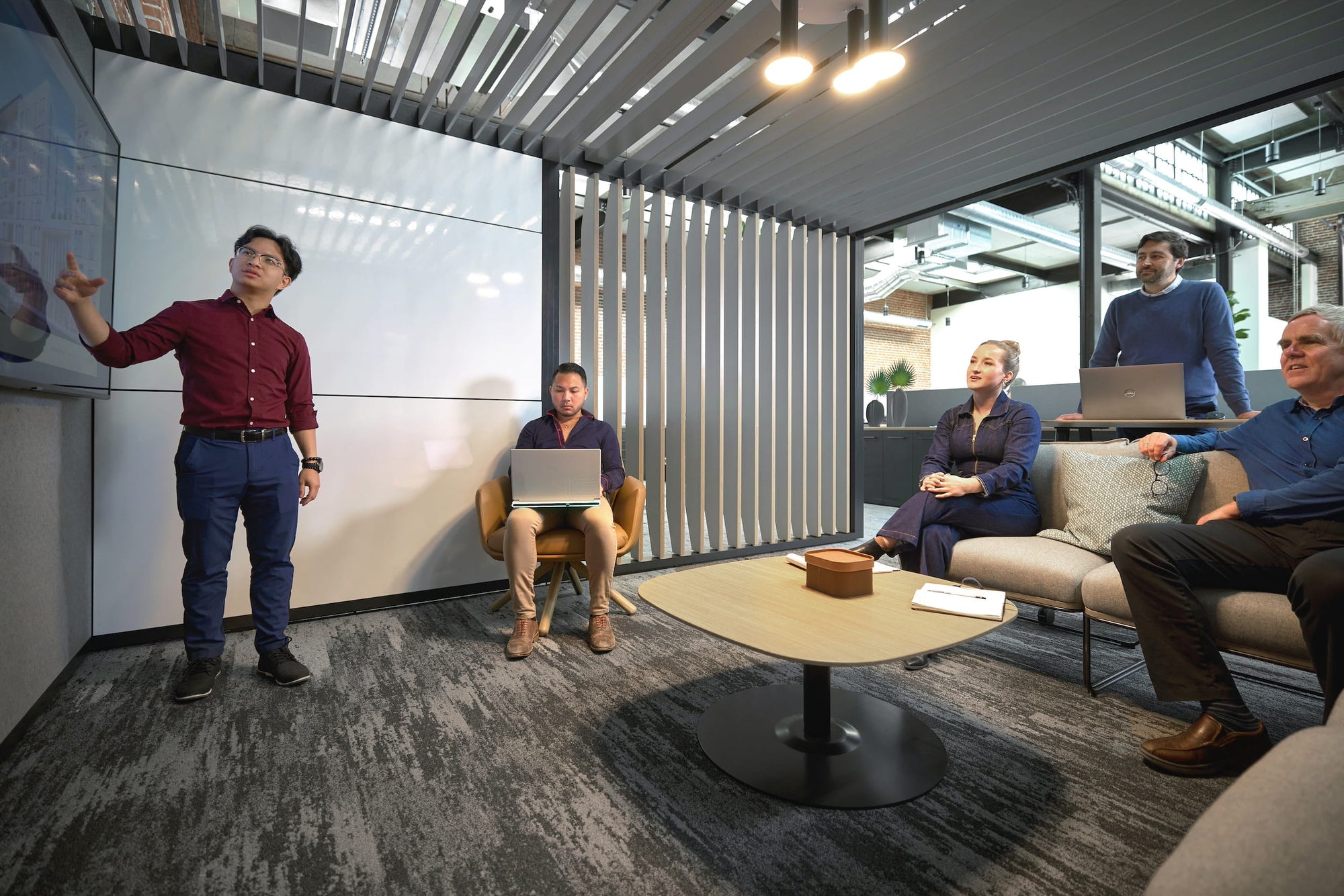 Group of people in a modern office setting with a presenter using a whiteboard.