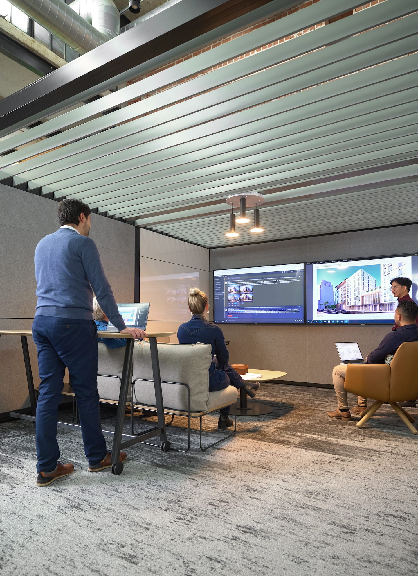 Group of people in a modern office setting with large screens displaying presentations.