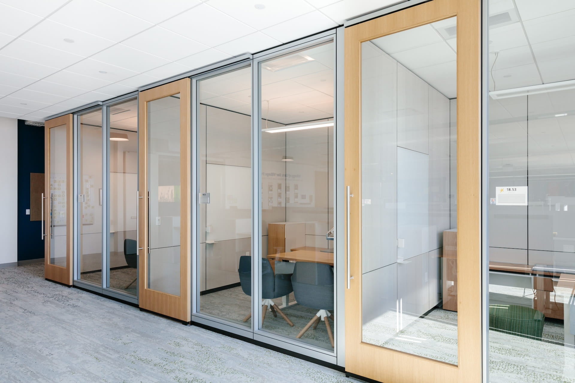 Modern office with glass-walled cubicles and wooden frames.