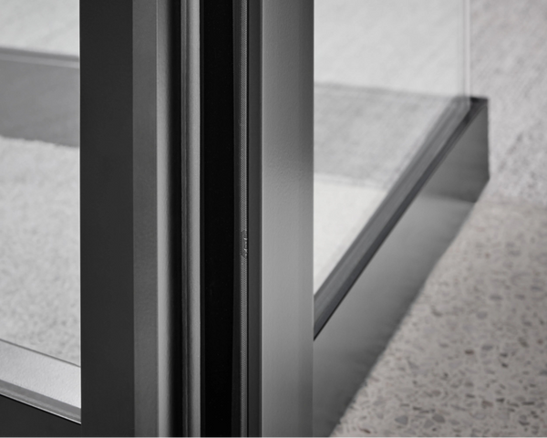 Close-up of a modern glass table with metal legs on a concrete floor.