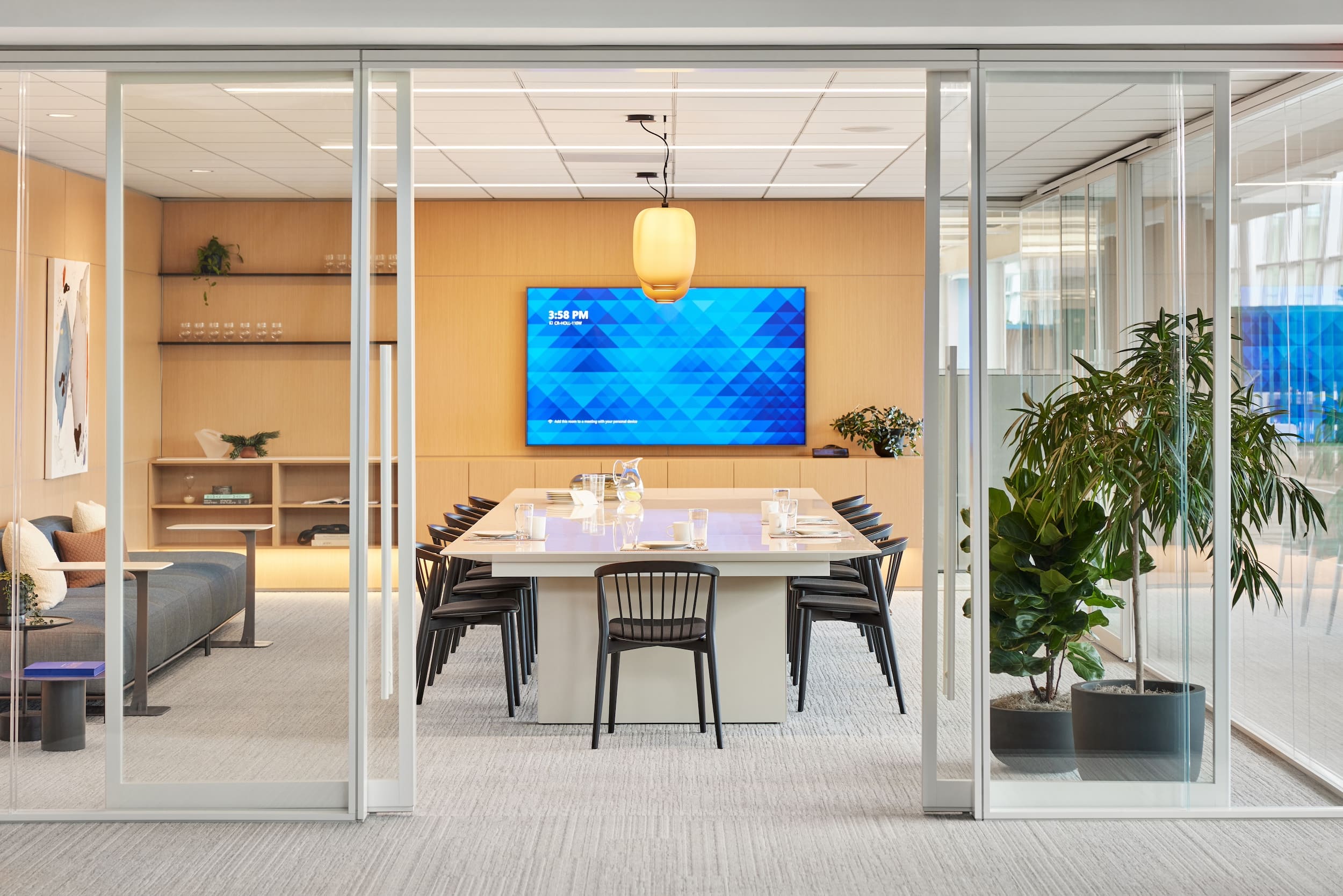 Modern office conference room with a large table, chairs, and a digital display on the wall.