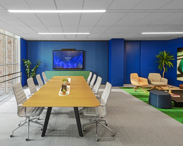 Modern office meeting room with a large table and chairs, and a blue wall with a screen.
