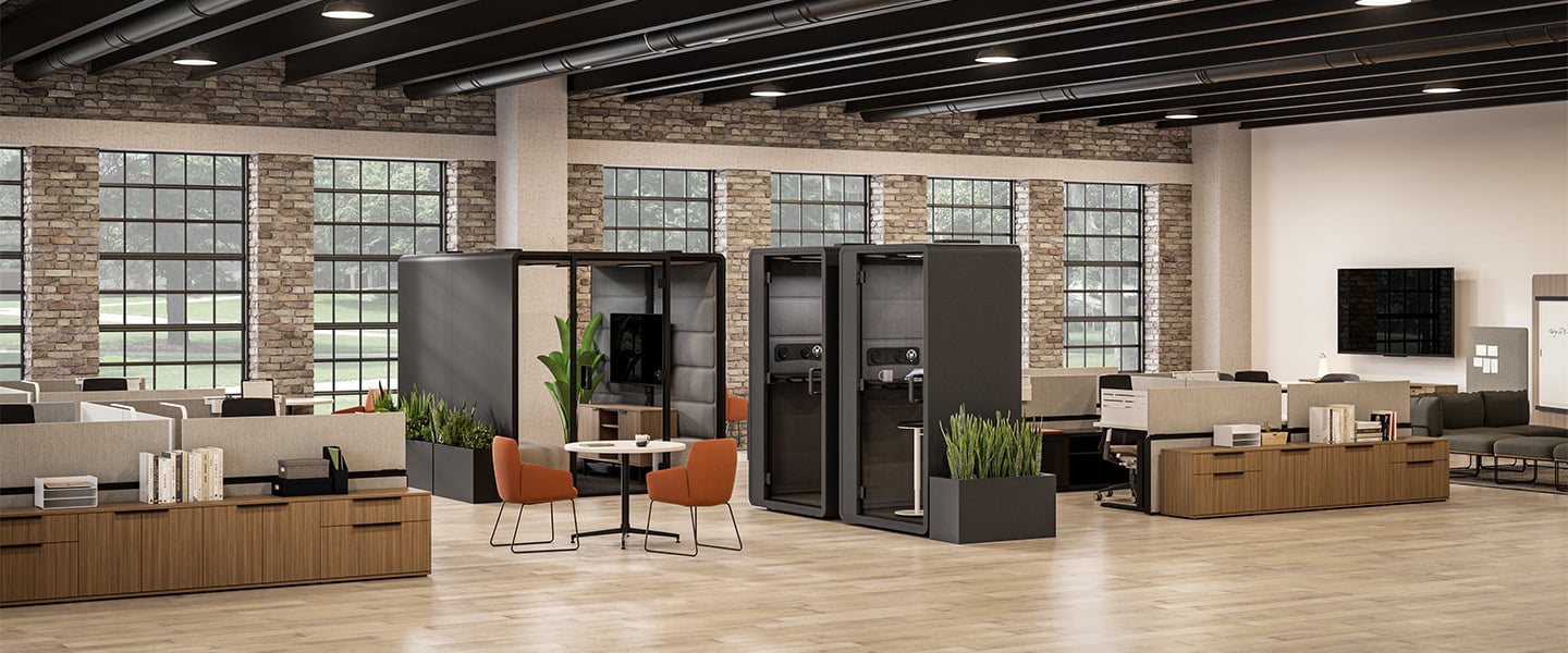 Modern office space with wooden desks, chairs, and a brick wall.