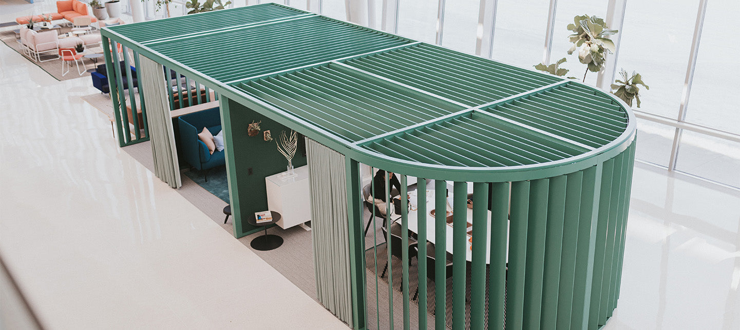 Green metal office desk with a modern office setting in the background