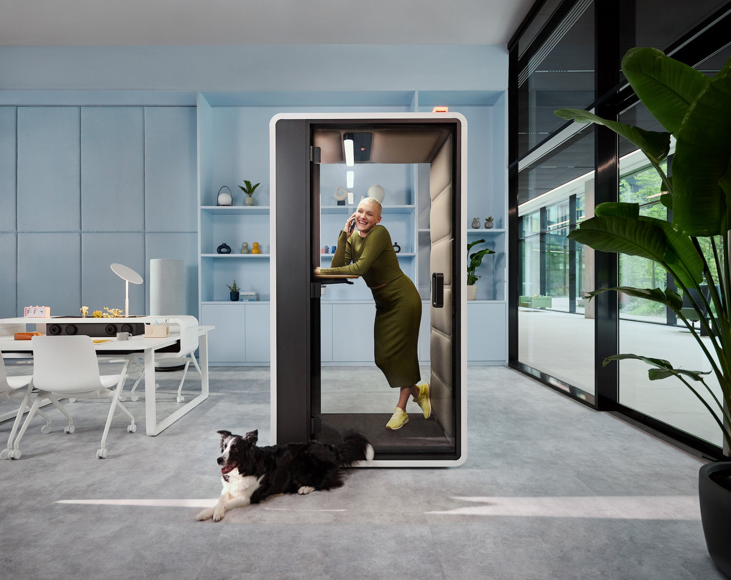 Person using a modern video doorbell in an office setting with a dog nearby.