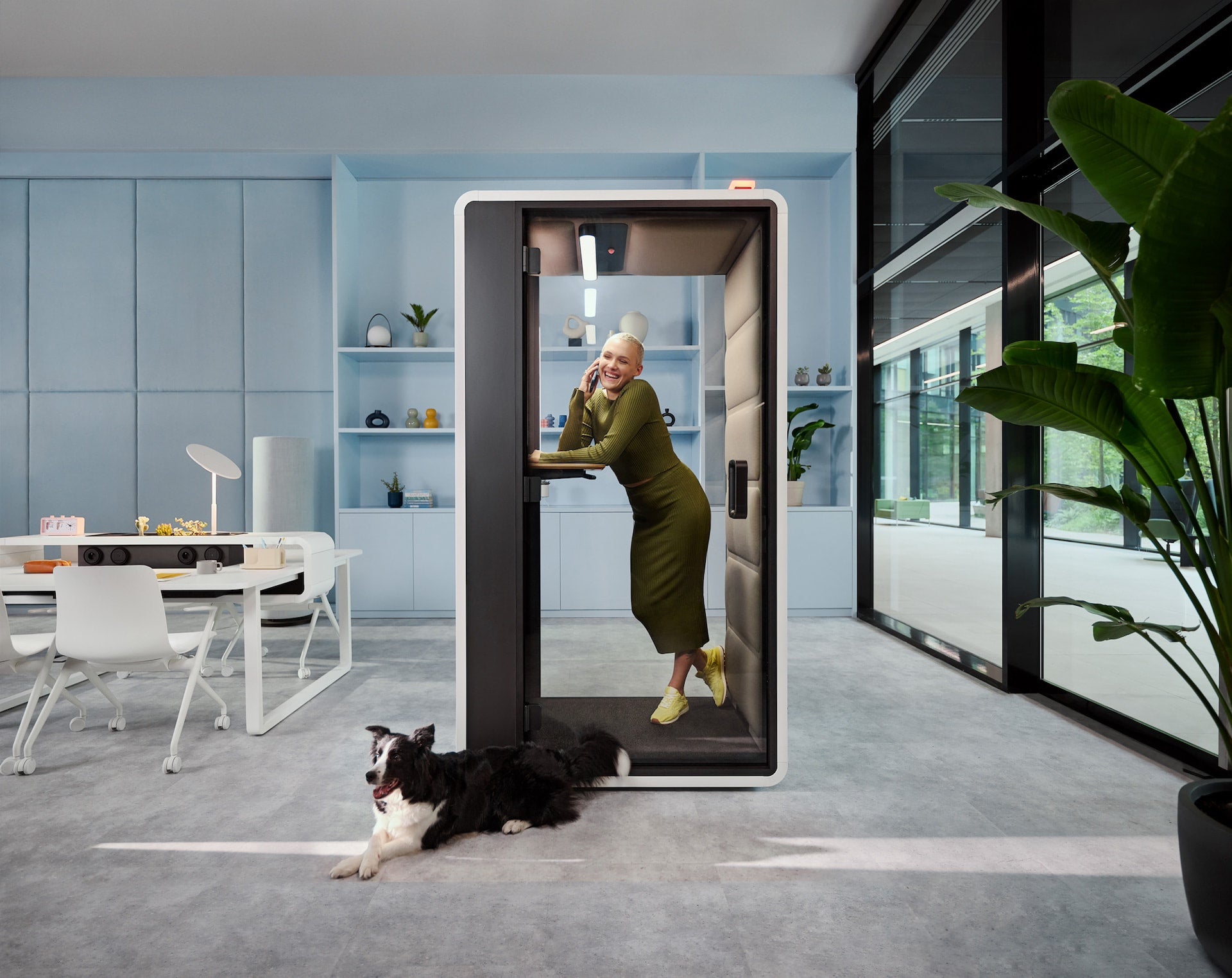 Person using a modern video doorbell in an office setting with a dog nearby.