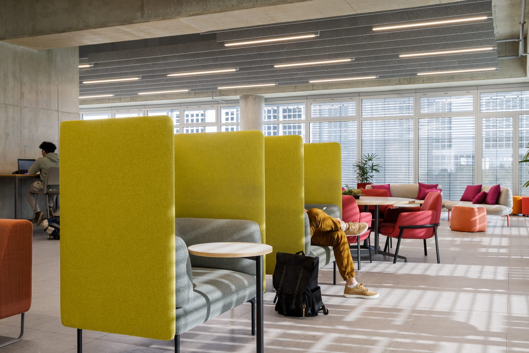 Modern office space with yellow partitioned workstations and red chairs.