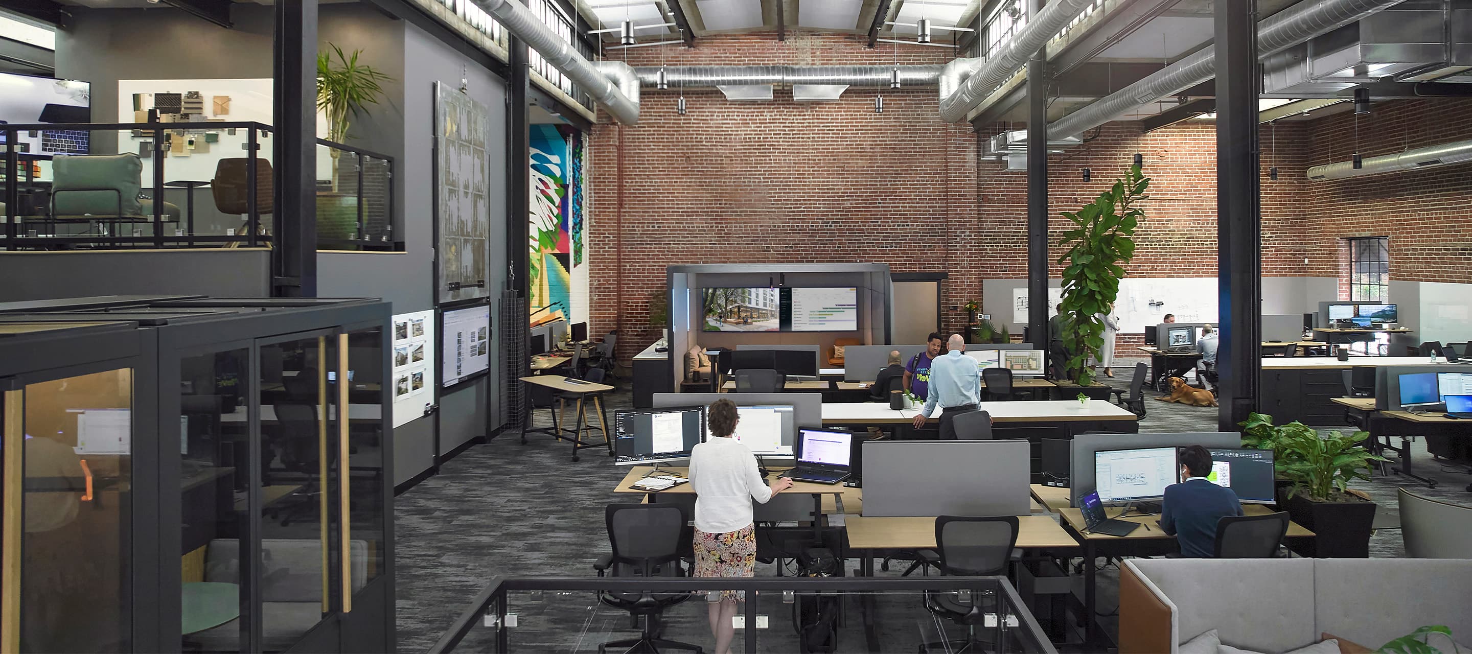 Modern office space with open-plan layout, desks, and computers.