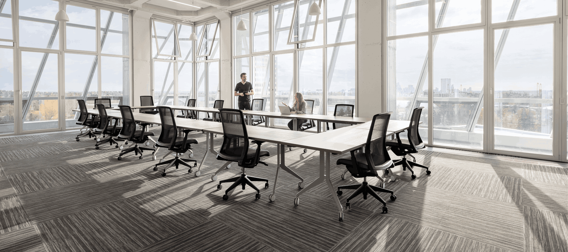 Modern office with large windows and a long table with chairs.