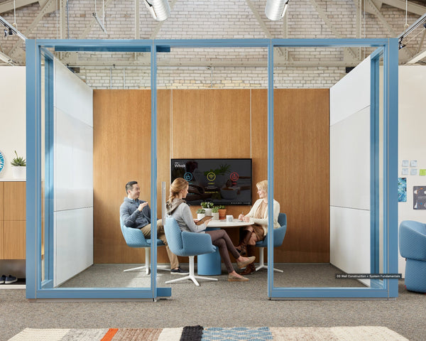 Modern office space with glass partition and people working together.